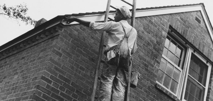 Man painting the side of a brick house