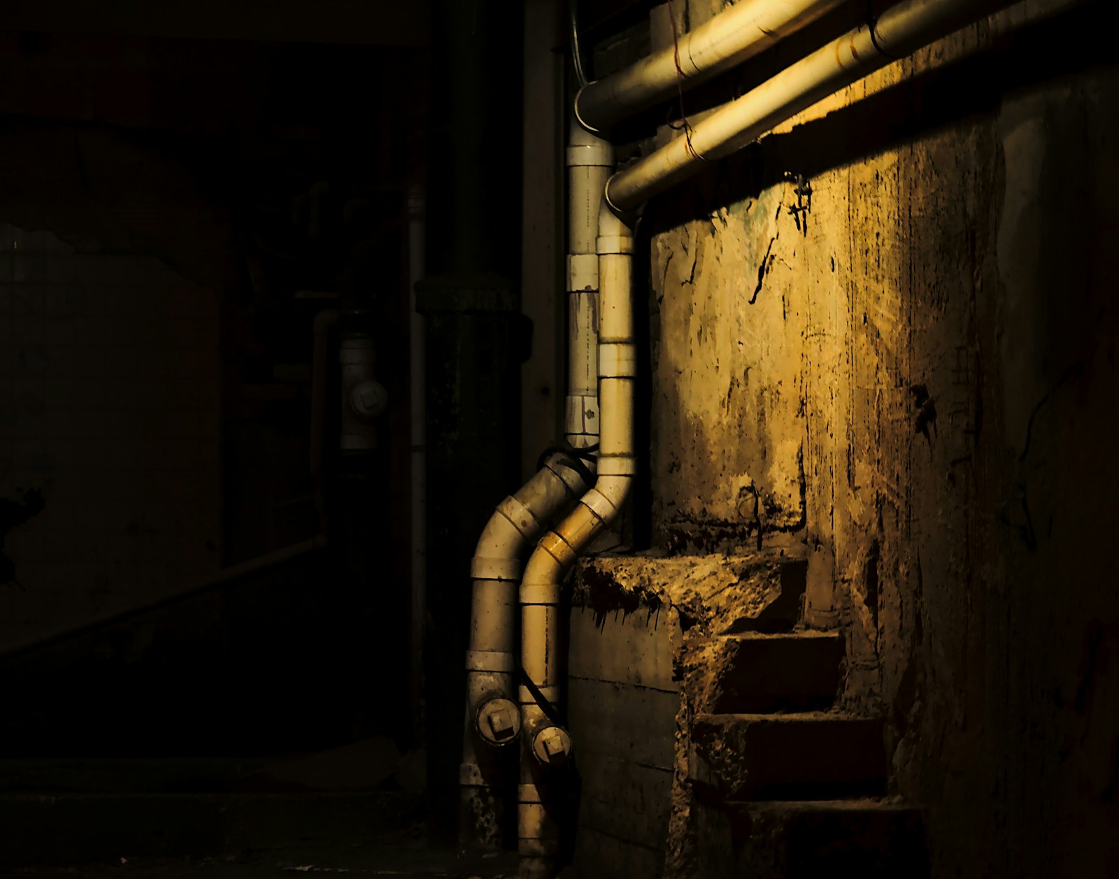 Dark basement with exposed pipes and a window, where hidden moisture can collect