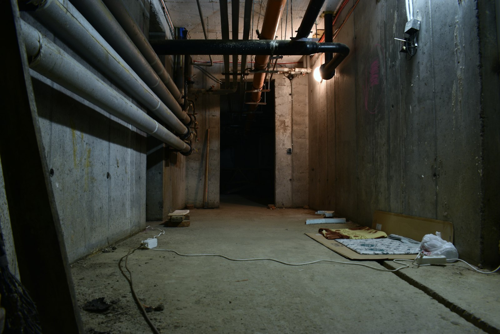 Dark basement room with exposed pipes, where water damage often starts