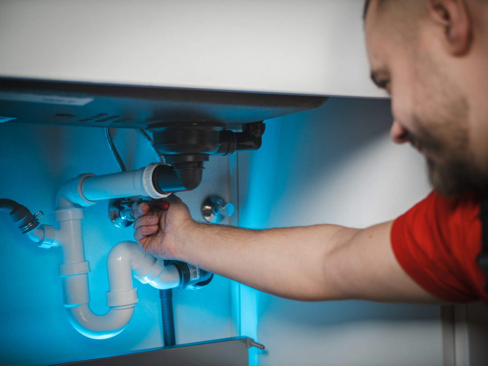 Technician working on a pipe inside a wall to stop a water leak